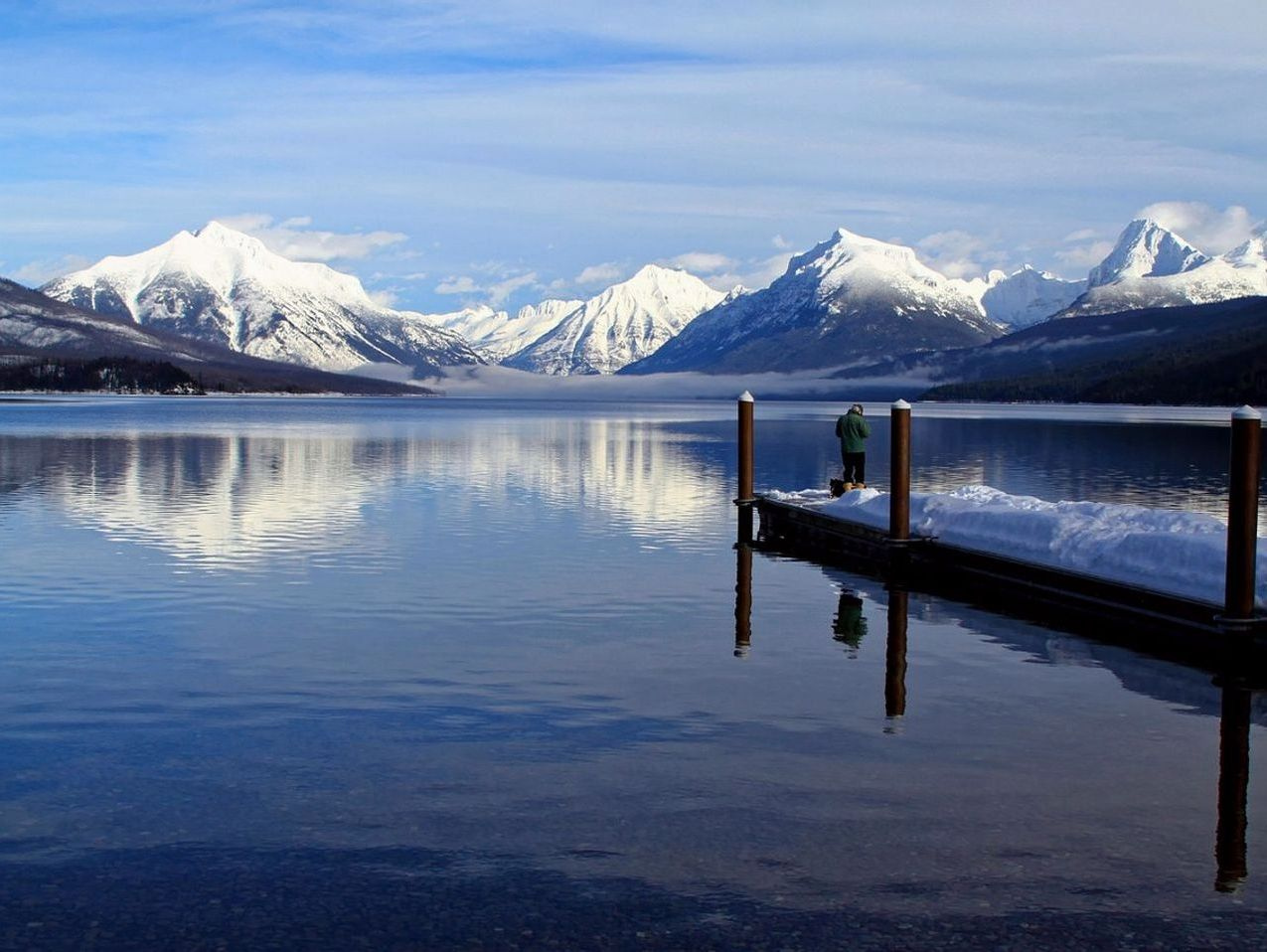 Agua tranquila del lago bajo el hielo reflejando montañas