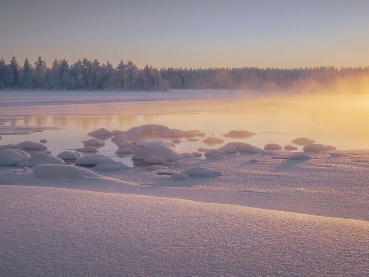 Taladro de pesca sobre hielo en lago de montaña al amanecer